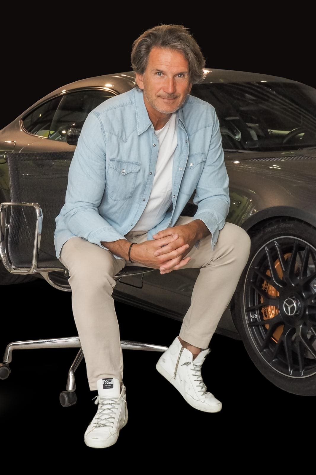 Markus Kalweit, founder of Everstern, sits on an office chair in front of a Mercedes-Benz sports car, looking at the camera.